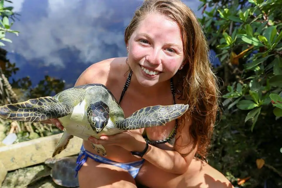 Chica sosteniendo tortuga marina y sonriendo