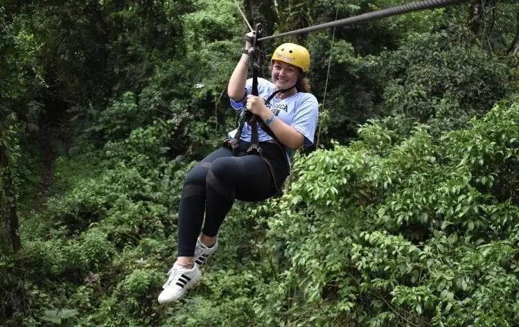 Volunteer zip-lining through rainforest
